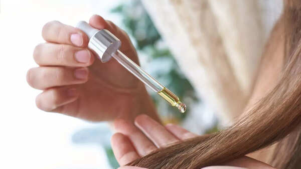 Woman applying hair serum to her hair.